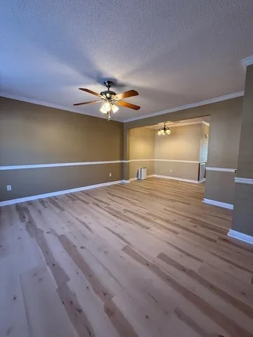 a view of an empty room with a chandelier fan and wooden floor