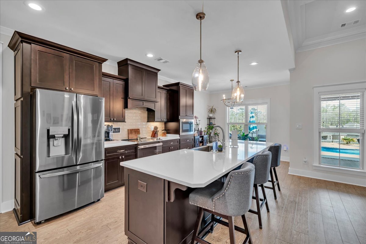 424 Rustic Live Oak Trail Bonaire, GA 31005 - Photo 11 of 51 a kitchen with stainless steel appliances a dining table chairs and wooden floor