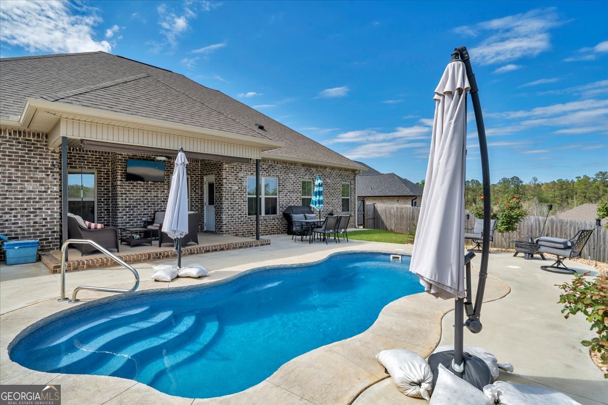 424 Rustic Live Oak Trail Bonaire, GA 31005 - Photo 49 of 51 a view of a patio with a dining table and chairs with wooden floor and fence