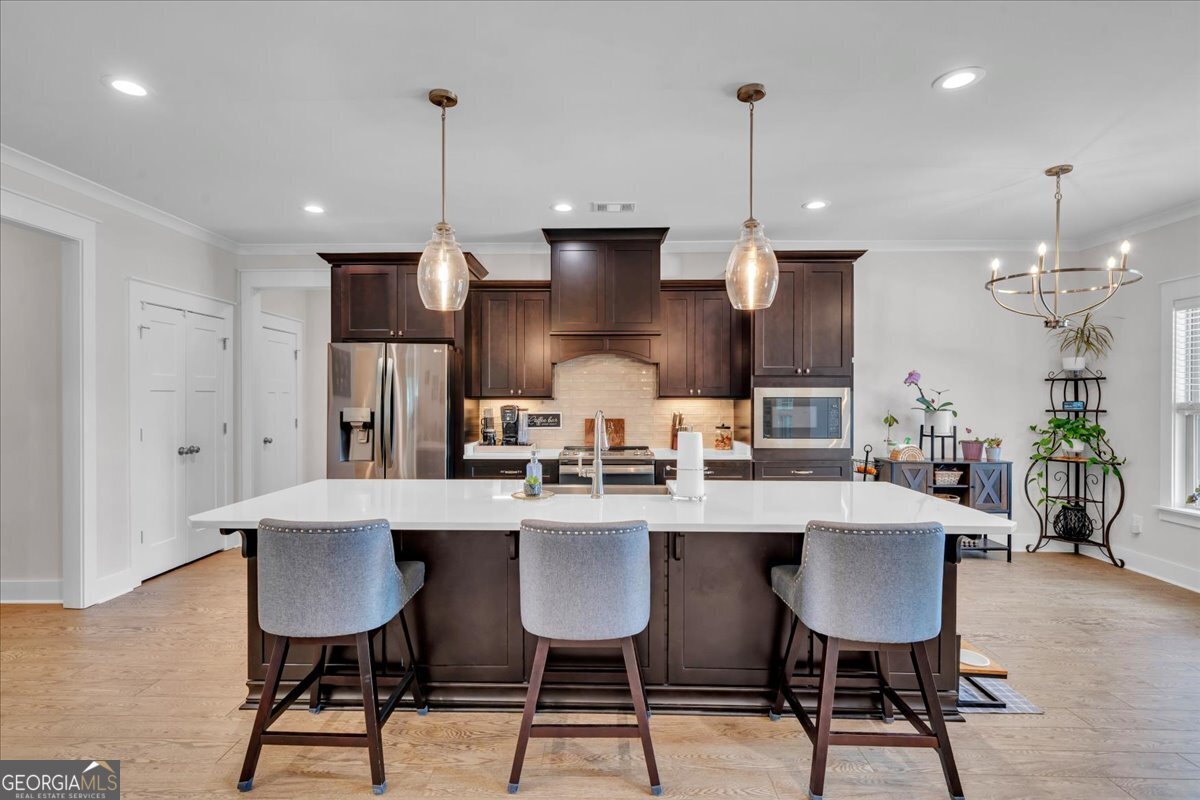 424 Rustic Live Oak Trail Bonaire, GA 31005 - Photo 10 of 51 a kitchen with stainless steel appliances a dining table chairs stove and white cabinets