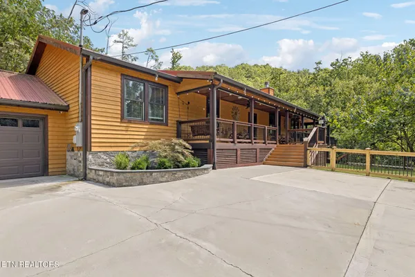 a view of house with backyard and trees in the background