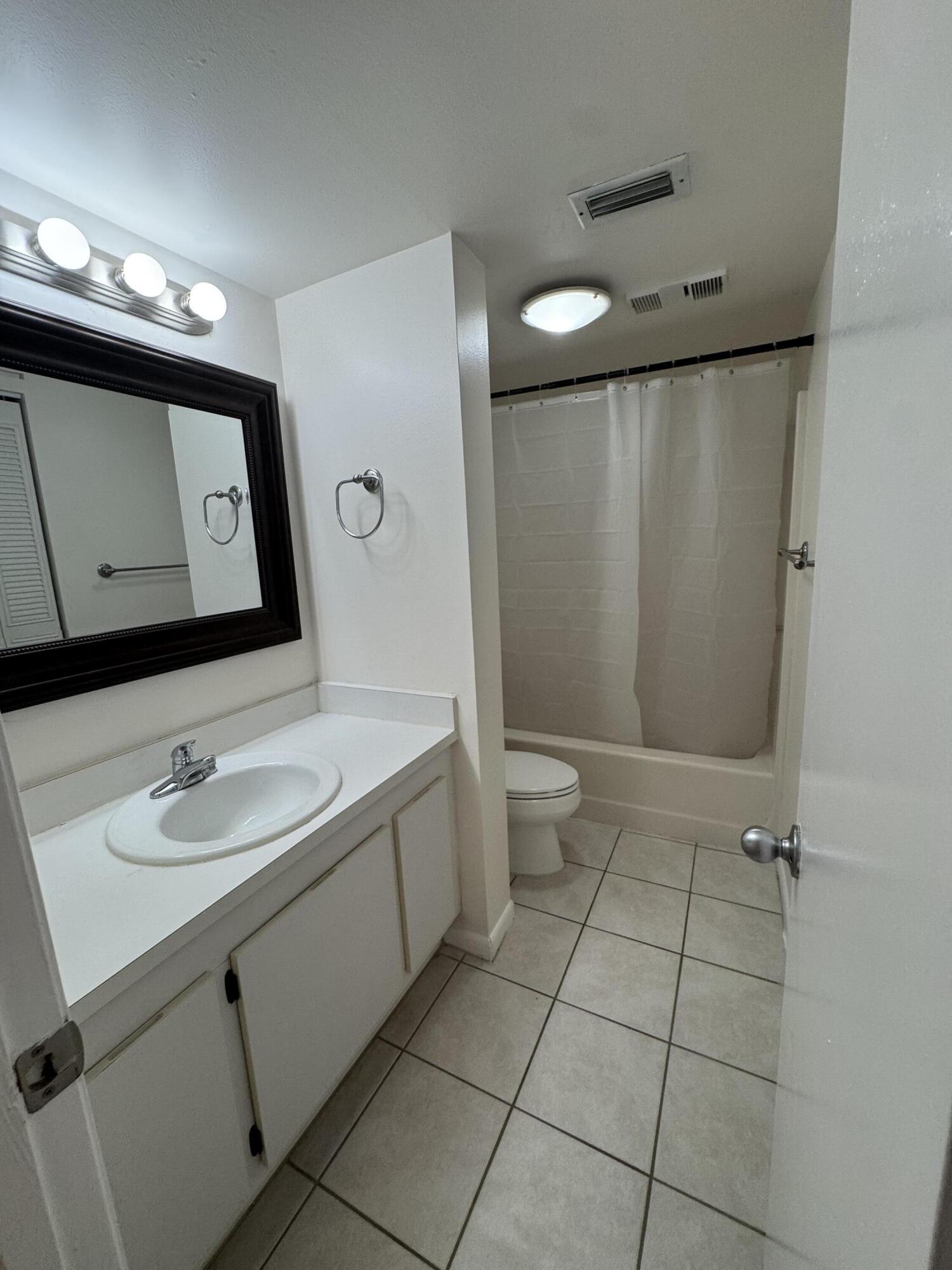 21890 Lake Forest Circle, Unit 102 Boca Raton, FL 33433 - Photo 13 of 24 a bathroom with a toilet sink and mirror