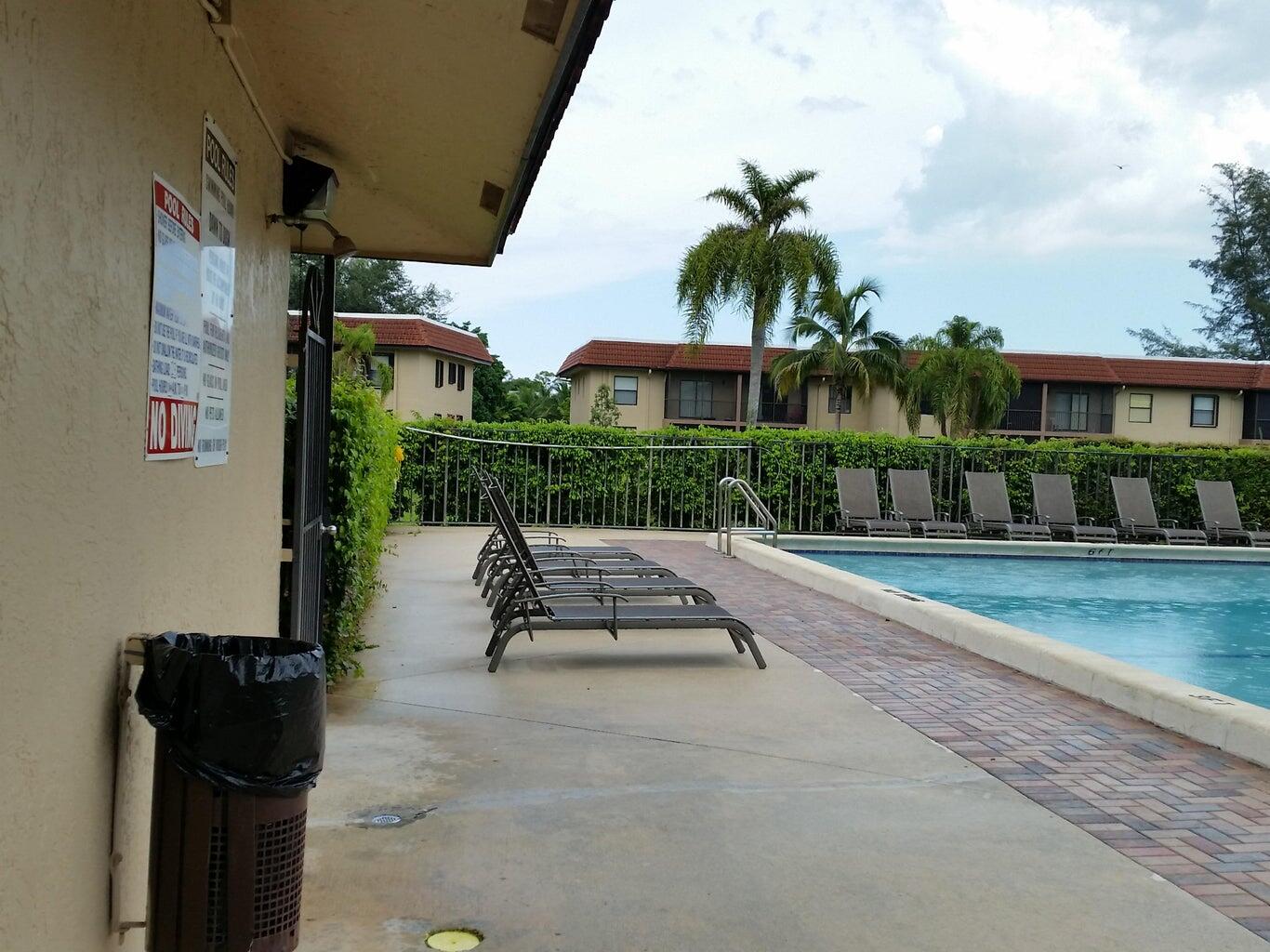 21890 Lake Forest Circle, Unit 102 Boca Raton, FL 33433 - Photo 23 of 24 a view of a patio with a table and chairs under an umbrella