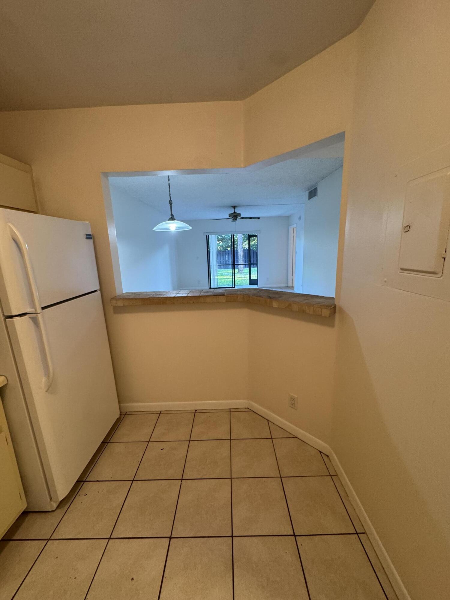 21890 Lake Forest Circle, Unit 102 Boca Raton, FL 33433 - Photo 5 of 24 a view of a refrigerator in kitchen and an empty room