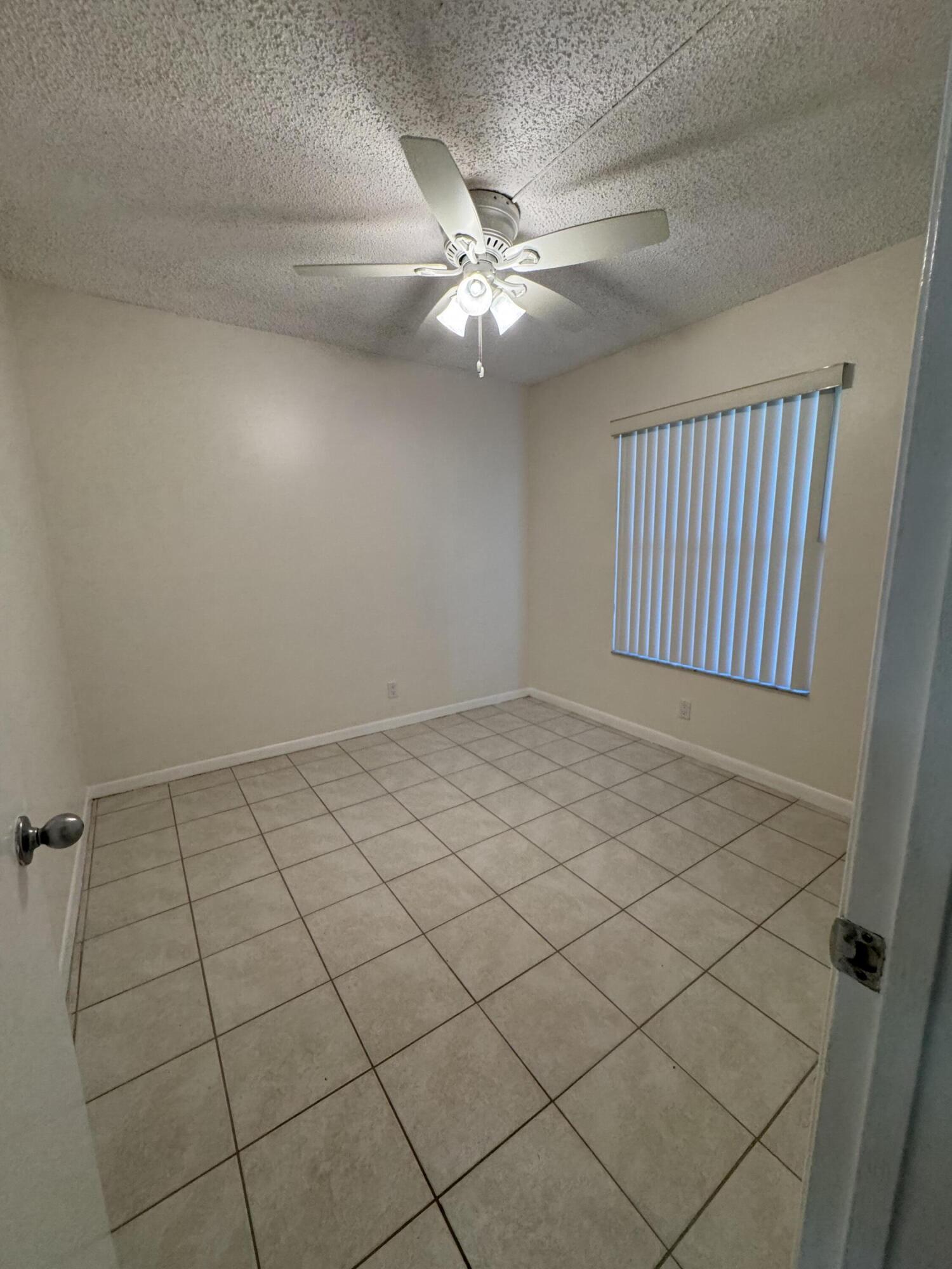 21890 Lake Forest Circle, Unit 102 Boca Raton, FL 33433 - Photo 9 of 24 en empty room with windows and ceiling fan