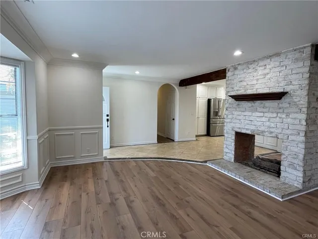 an empty room with wooden floor a fireplace and windows