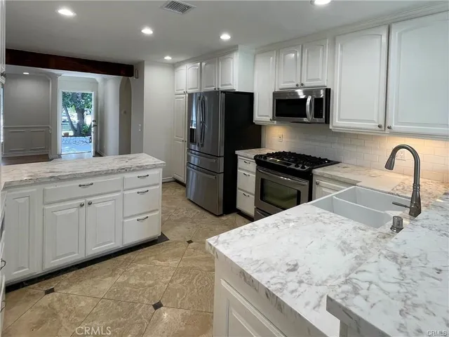 a kitchen with stainless steel appliances granite countertop a sink a stove a refrigerator and a oven