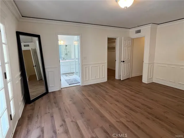 a view of a hallway with wooden floor and a bathroom