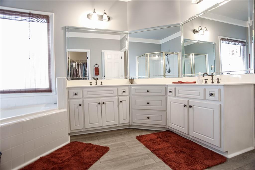 3875 Spring Manor Court Loganville, GA 30052 - Photo 22 of 23 a spacious bathroom with a sink a mirror a vanity and a bathtub