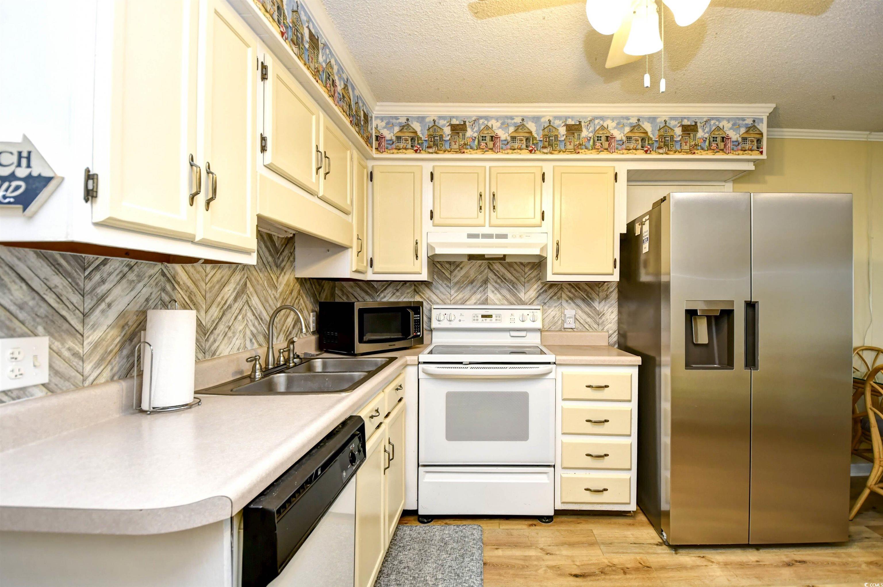 191 Maison Drive, Unit B211 Myrtle Beach, SC 29572 - Photo 11 of 35 Kitchen with appliances with stainless steel finishes, a textured ceiling, light countertops, tasteful backsplash, and ceiling fan