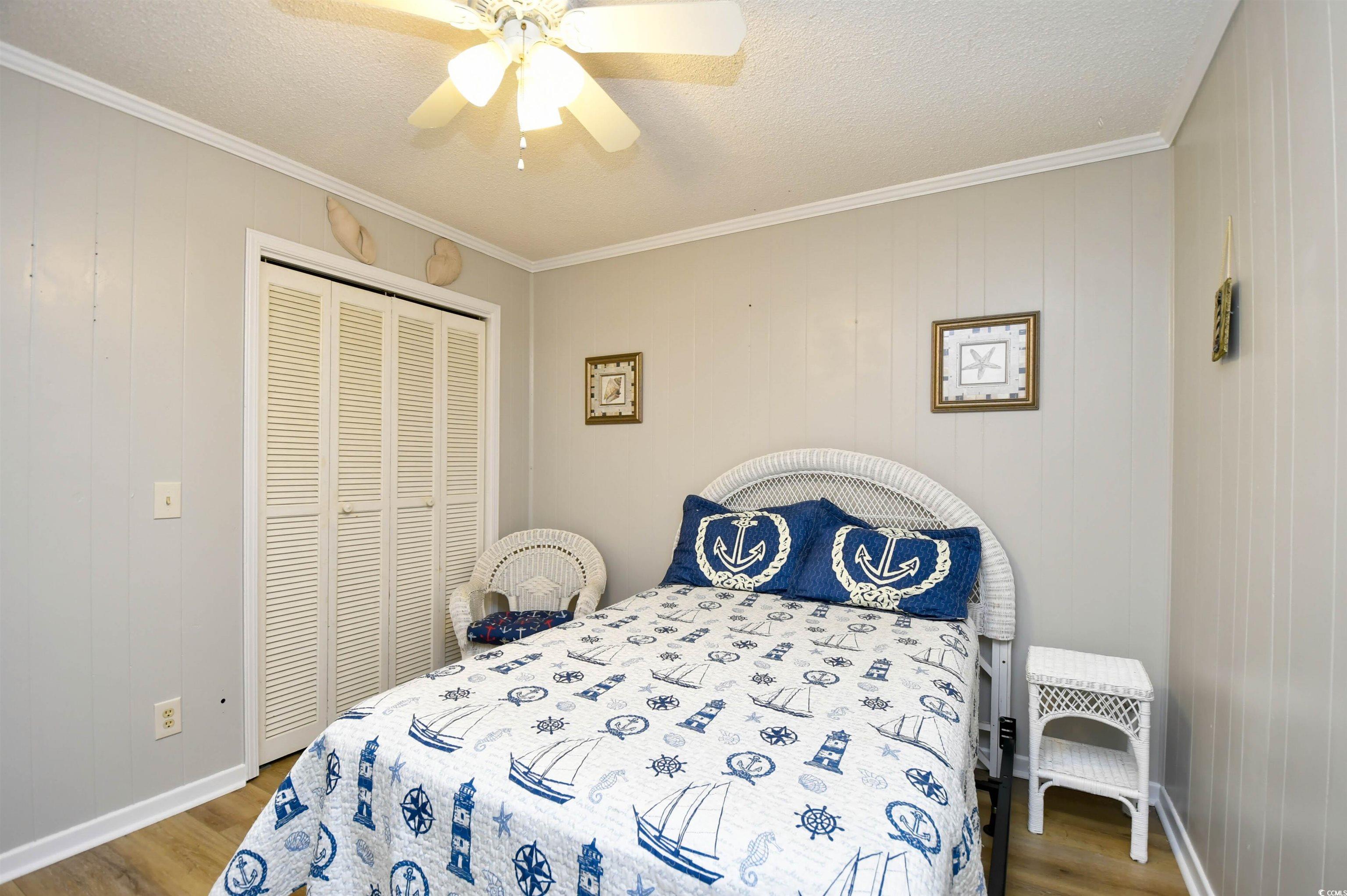 191 Maison Drive, Unit B211 Myrtle Beach, SC 29572 - Photo 18 of 35 Bedroom with ornamental molding, wood walls, wood finished floors, ceiling fan, and a textured ceiling