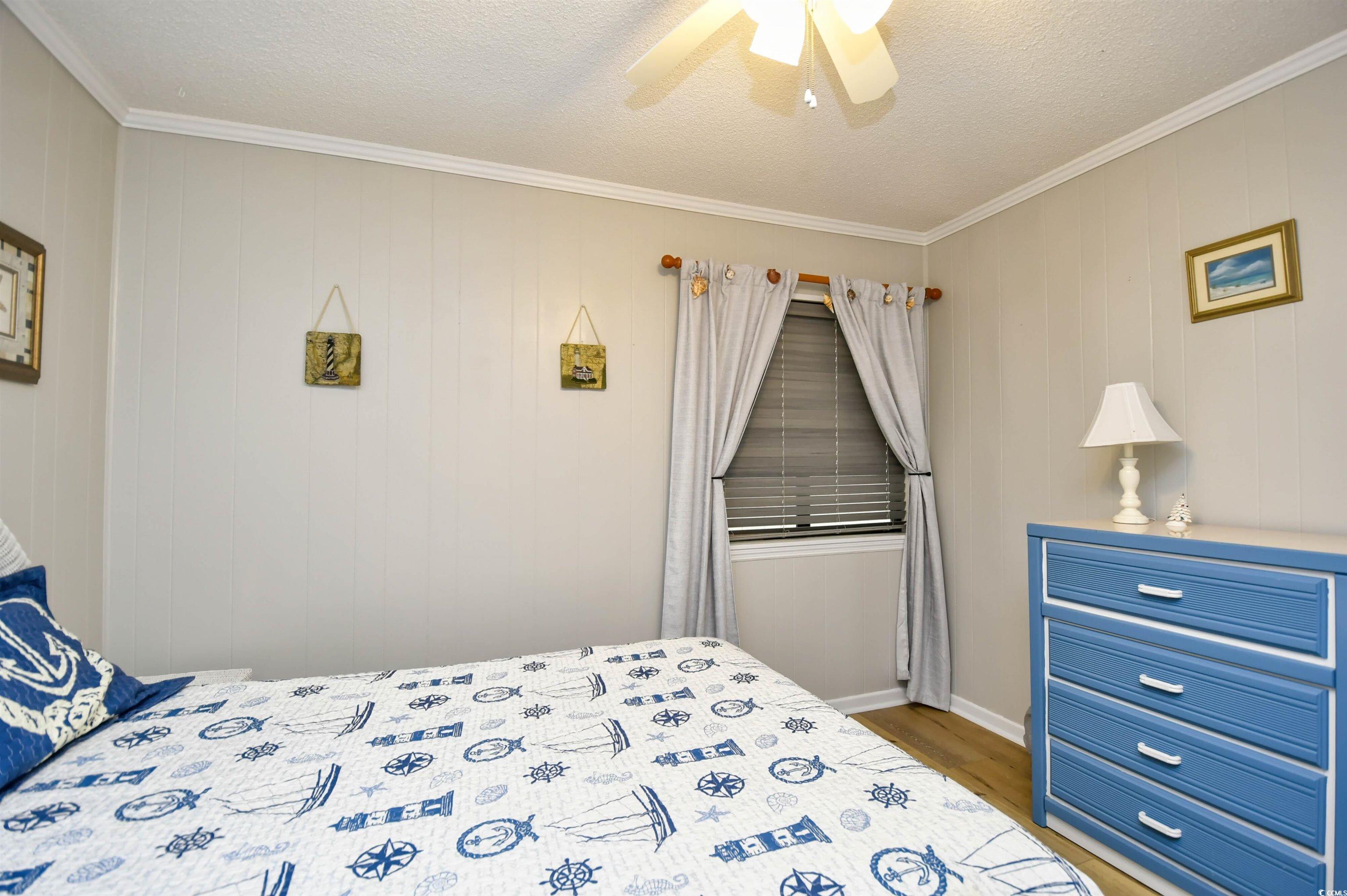 191 Maison Drive, Unit B211 Myrtle Beach, SC 29572 - Photo 19 of 35 Bedroom featuring ornamental molding, wood finished floors, a ceiling fan, and a textured ceiling