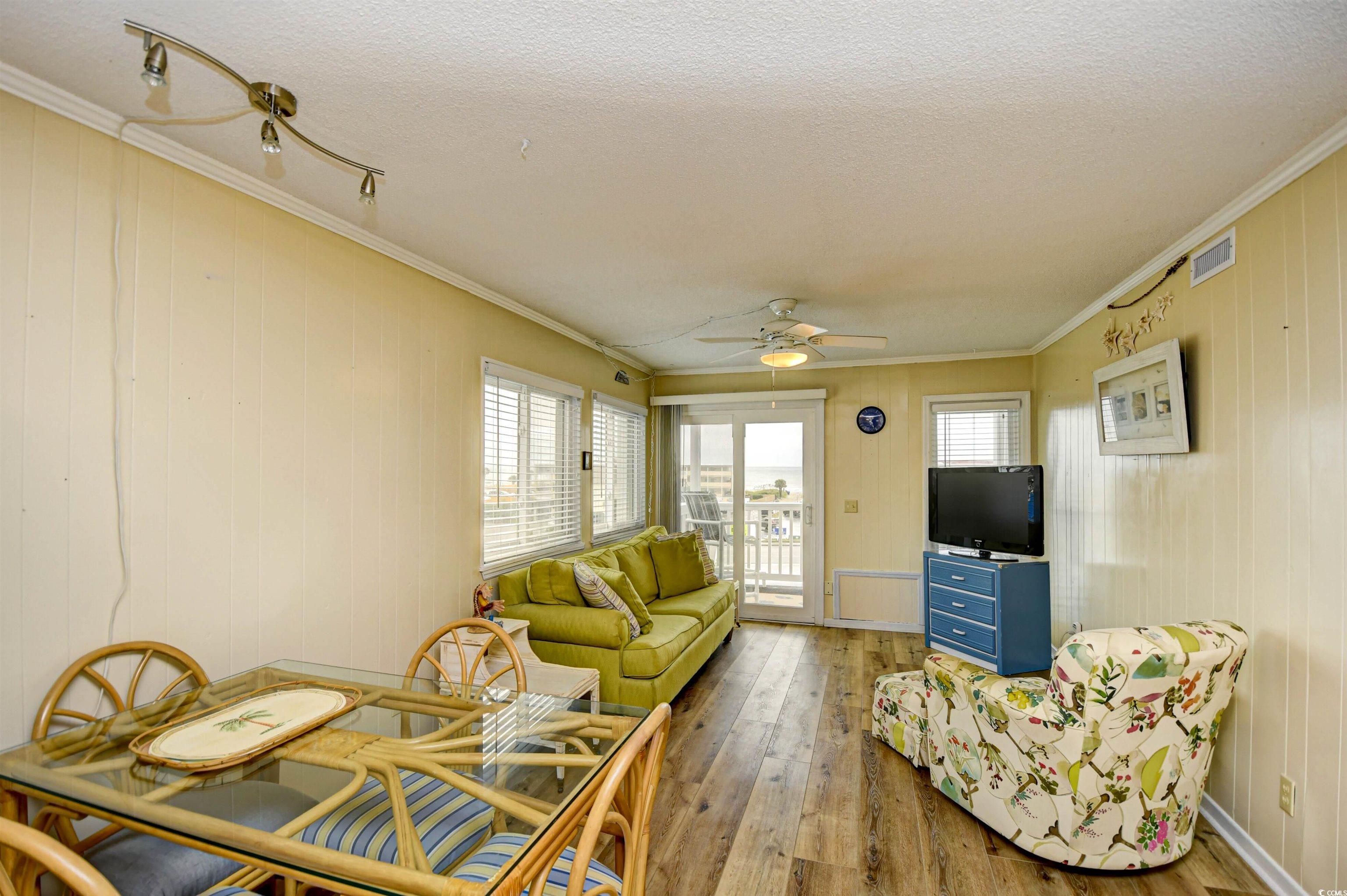 191 Maison Drive, Unit B211 Myrtle Beach, SC 29572 - Photo 4 of 35 Living area featuring plenty of natural light, crown molding, hardwood / wood-style flooring, wood walls, and a textured ceiling