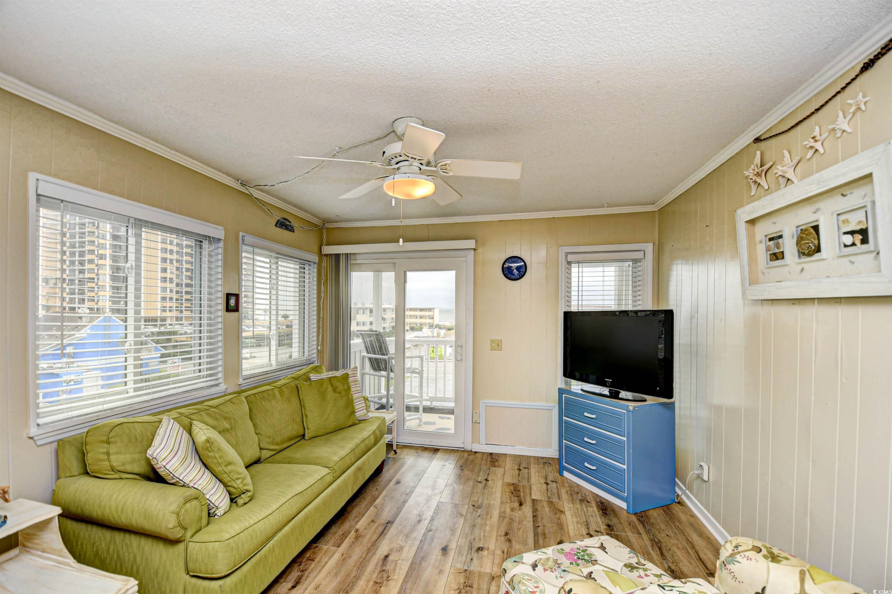 191 Maison Drive, Unit B211 Myrtle Beach, SC 29572 - Photo 5 of 35 Living room with crown molding, wood finished floors, a textured ceiling, a ceiling fan, and wood walls