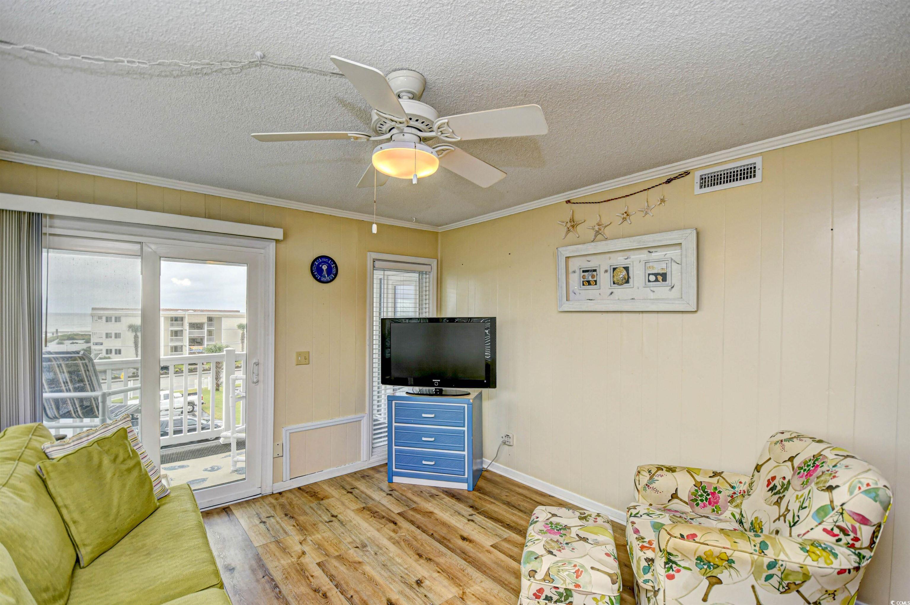 191 Maison Drive, Unit B211 Myrtle Beach, SC 29572 - Photo 6 of 35 Living area with healthy amount of natural light, ornamental molding, wood finished floors, wood walls, and ceiling fan
