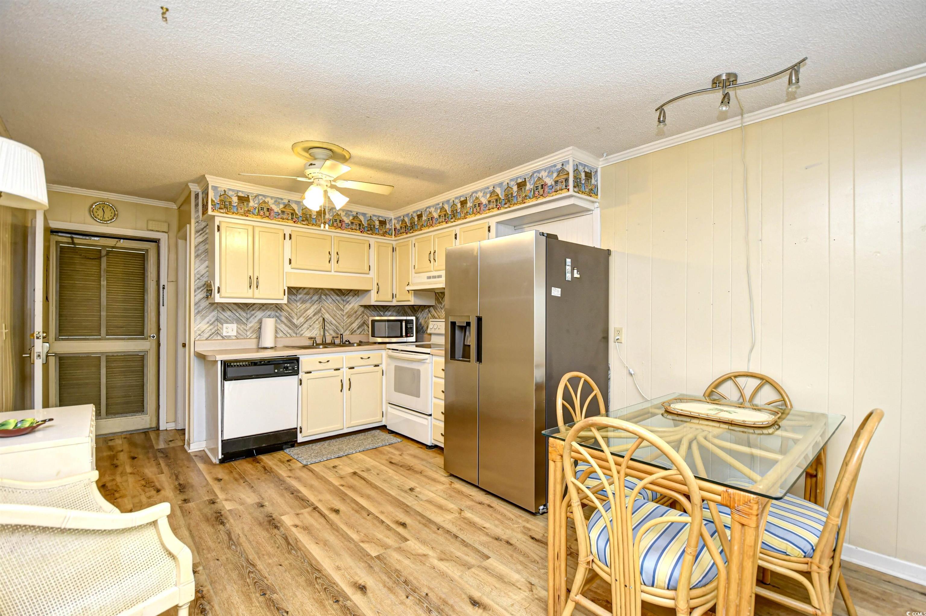 191 Maison Drive, Unit B211 Myrtle Beach, SC 29572 - Photo 9 of 35 Kitchen featuring stainless steel appliances, light wood-style floors, light countertops, tasteful backsplash, and a textured ceiling