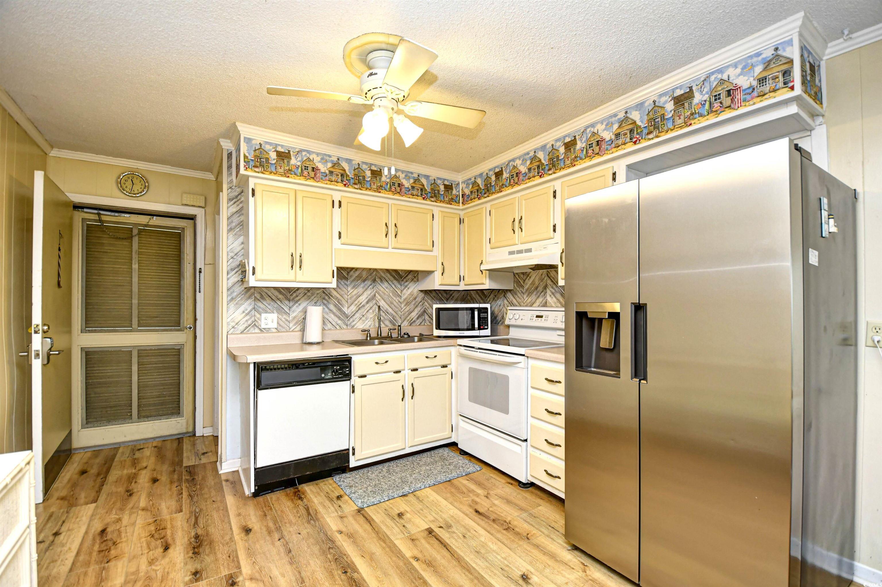 191 Maison Drive, Unit B211 Myrtle Beach, SC 29572 - Photo 10 of 35 Kitchen with appliances with stainless steel finishes, light countertops, a textured ceiling, light wood-style flooring, and crown molding