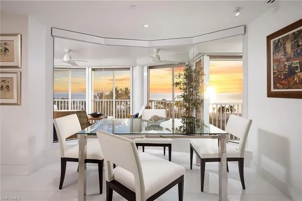 a dining room with furniture large windows and a chandelier