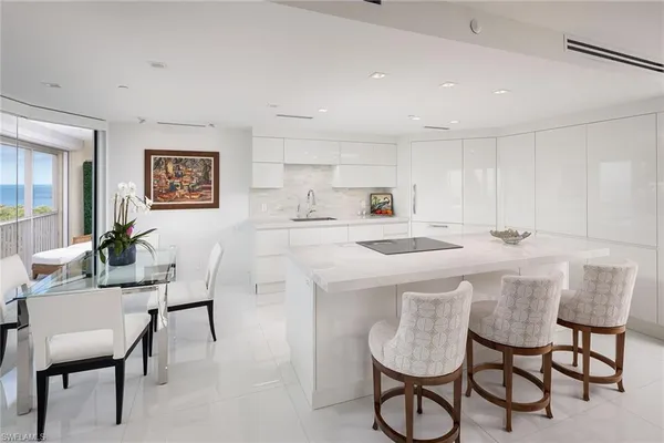 a kitchen with stainless steel appliances granite countertop a dining table chairs and a refrigerator