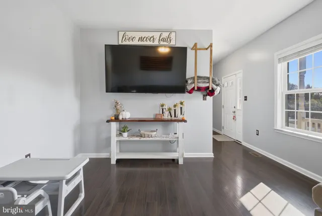 a living room with a flat screen tv a rug and white walls