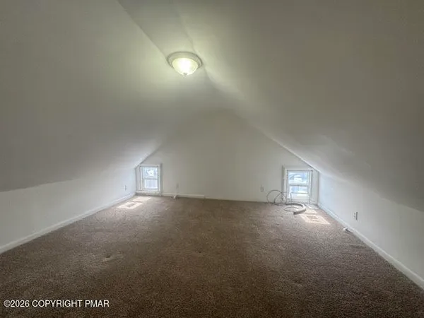 an empty room with windows and fireplace