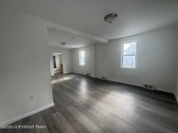 an empty room with wooden floor and windows