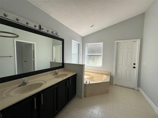 a spacious bathroom with a tub sink and mirror
