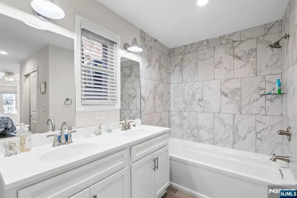 a bathroom with a double vanity sink mirror and a bathtub