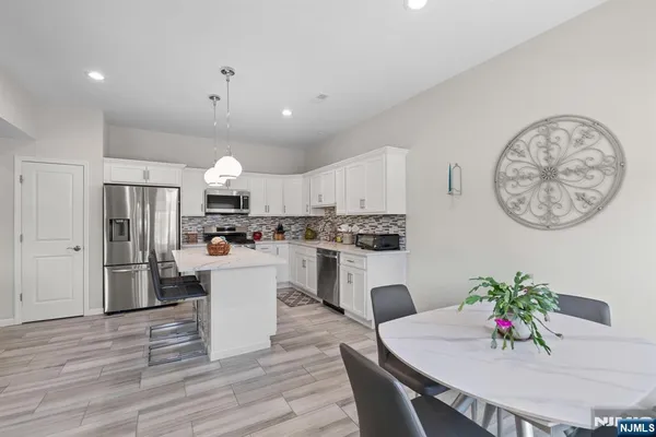 a kitchen with white cabinets stainless steel appliances and dining table