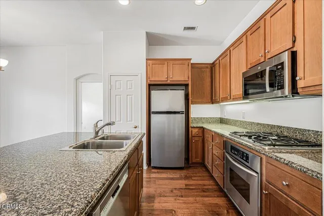 a kitchen with granite countertop a sink stove and refrigerator