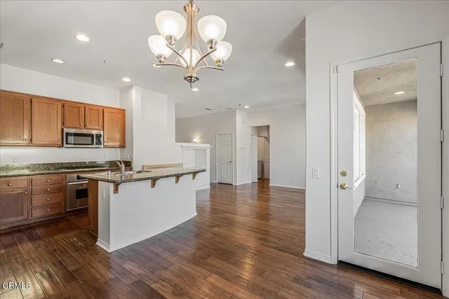 a large kitchen with stainless steel appliances granite countertop a stove top oven a refrigerator with wooden floors and cabinets