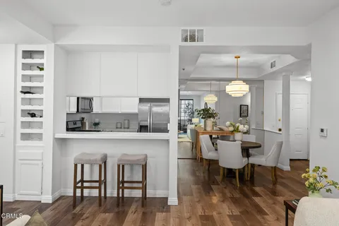a living room with stainless steel appliances furniture a rug and a view of kitchen