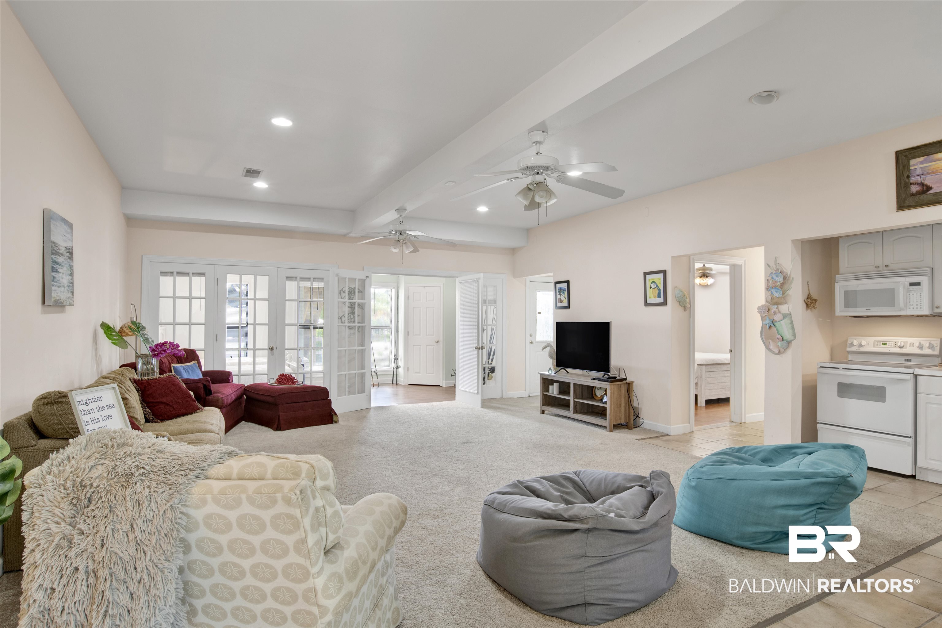 33093 River Road Orange Beach, AL 36561 - Photo 19 of 30 Living room featuring light tile patterned flooring, french doors, ceiling fan, and beam ceiling