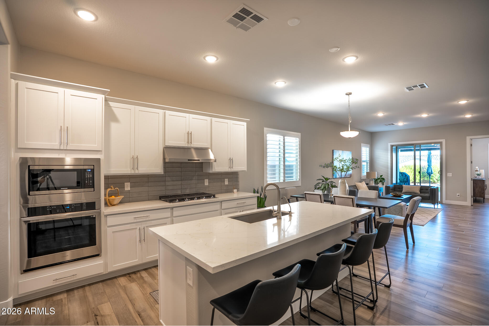 5693 206th Lane Buckeye, AZ 85396 - Photo 6 of 33 a kitchen with stainless steel appliances kitchen island granite countertop a stove a sink a dining table and chairs with wooden floor