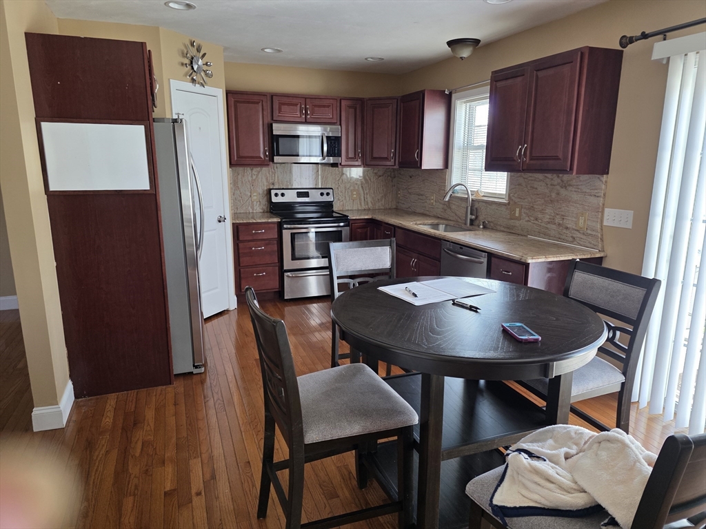 176 Oak Grove Avenue Fall River, MA 02723 - Photo 2 of 9 a kitchen with stainless steel appliances a table chairs and a refrigerator
