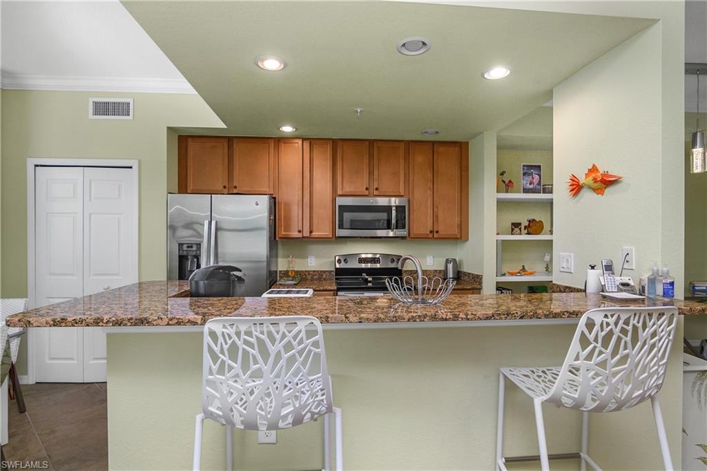 9832 Venezia Circle, Unit 1013 Naples, FL 34113 - Photo 17 of 34 a kitchen with stainless steel appliances granite countertop a sink refrigerator and microwave