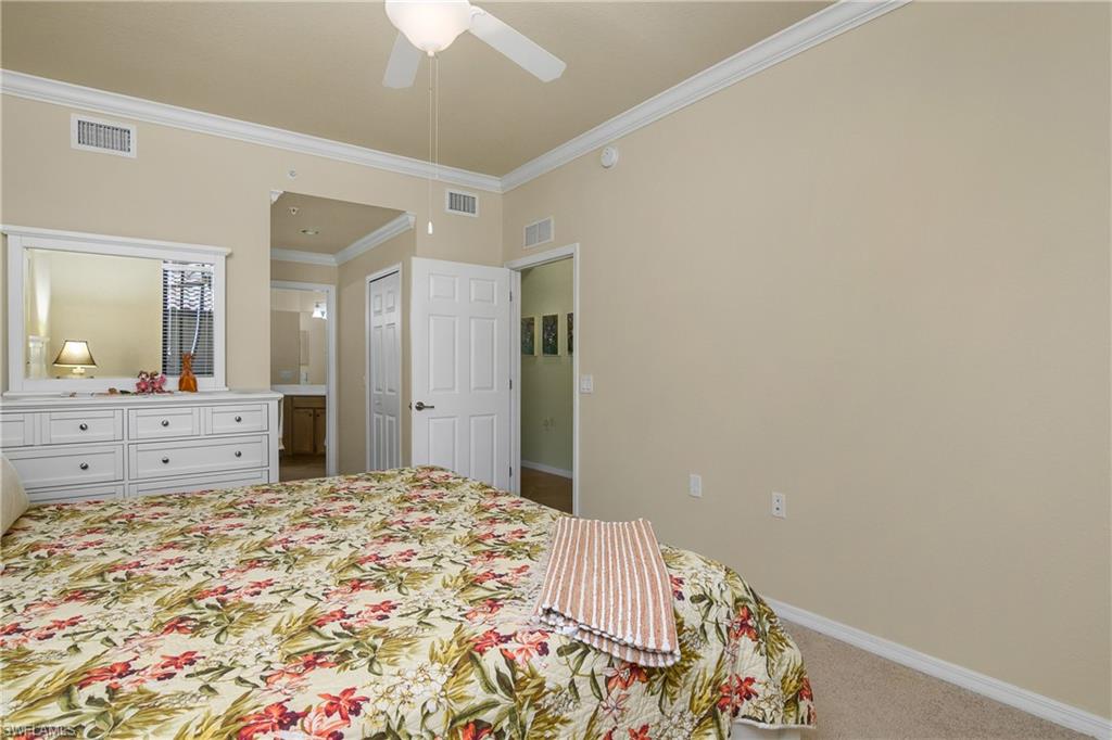 9832 Venezia Circle, Unit 1013 Naples, FL 34113 - Photo 23 of 34 a bedroom with a large bed and a mirror on dresser