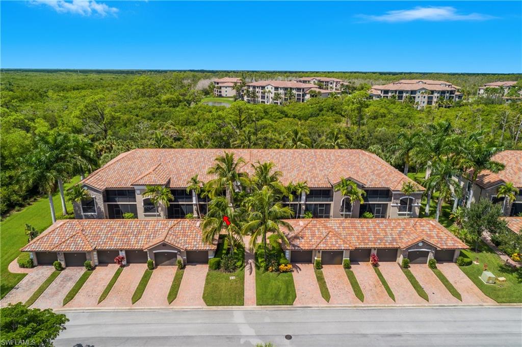 9832 Venezia Circle, Unit 1013 Naples, FL 34113 - Photo 31 of 34 a view of a patio with lawn chairs under an umbrella