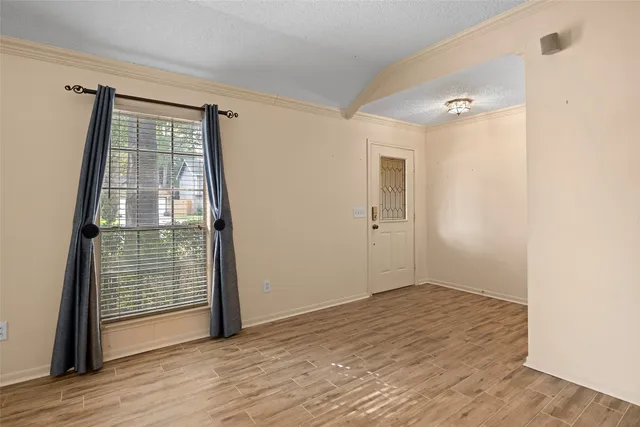 a view of an empty room with wooden floor and a window