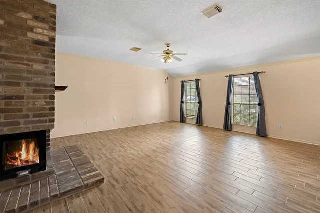 an empty room with windows and fireplace