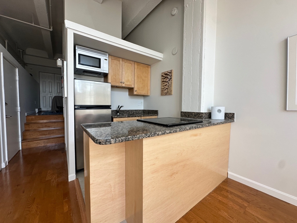 12 Stoneholm Street, Unit 529 Boston, MA 02115 - Photo 2 of 11 a kitchen with kitchen island granite countertop a refrigerator and a stove