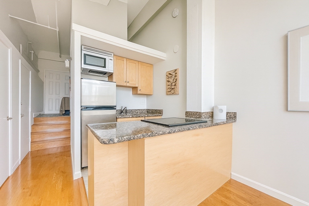 12 Stoneholm Street, Unit 529 Boston, MA 02115 - Photo 3 of 11 a kitchen with stainless steel appliances granite countertop a sink and a refrigerator