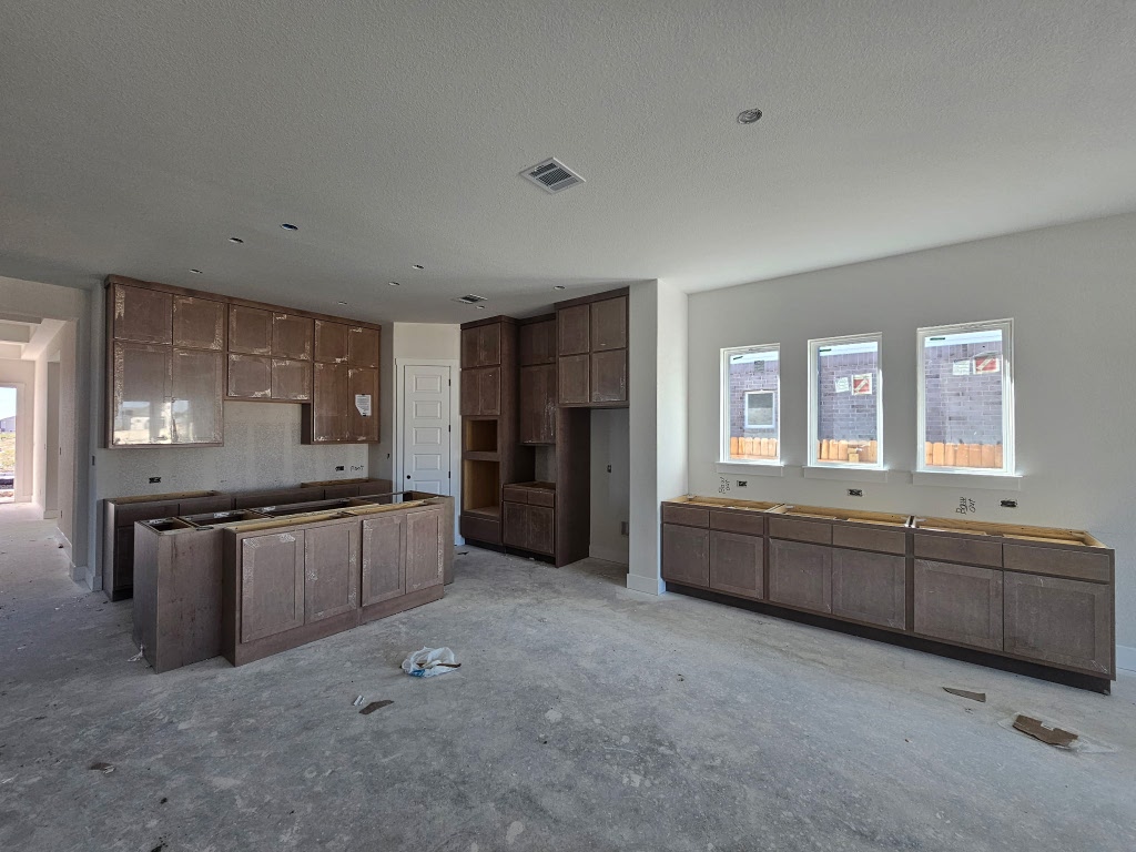 19608 Domino Champ Road Pflugerville, TX 78660 - Photo 2 of 14 a large kitchen with kitchen island granite countertop a large counter top space appliances and cabinets