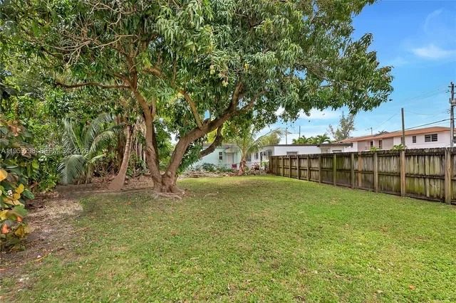 a view of a yard in front of a house with a large tree