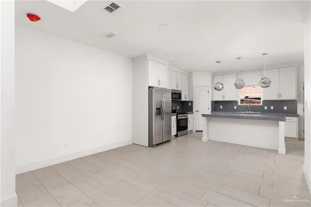 a kitchen with stainless steel appliances granite countertop a refrigerator stove and white cabinets