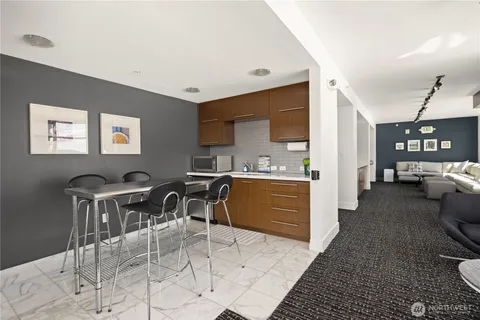 a living room with furniture a rug and white kitchen