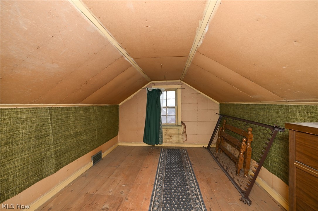 3699 Bainbridge Road Cleveland Heights, OH 44118 - Photo 33 of 37 Attic space featuring sloped ceilings, exposed wood flooring, a window with a green curtain, and textured green wall covering