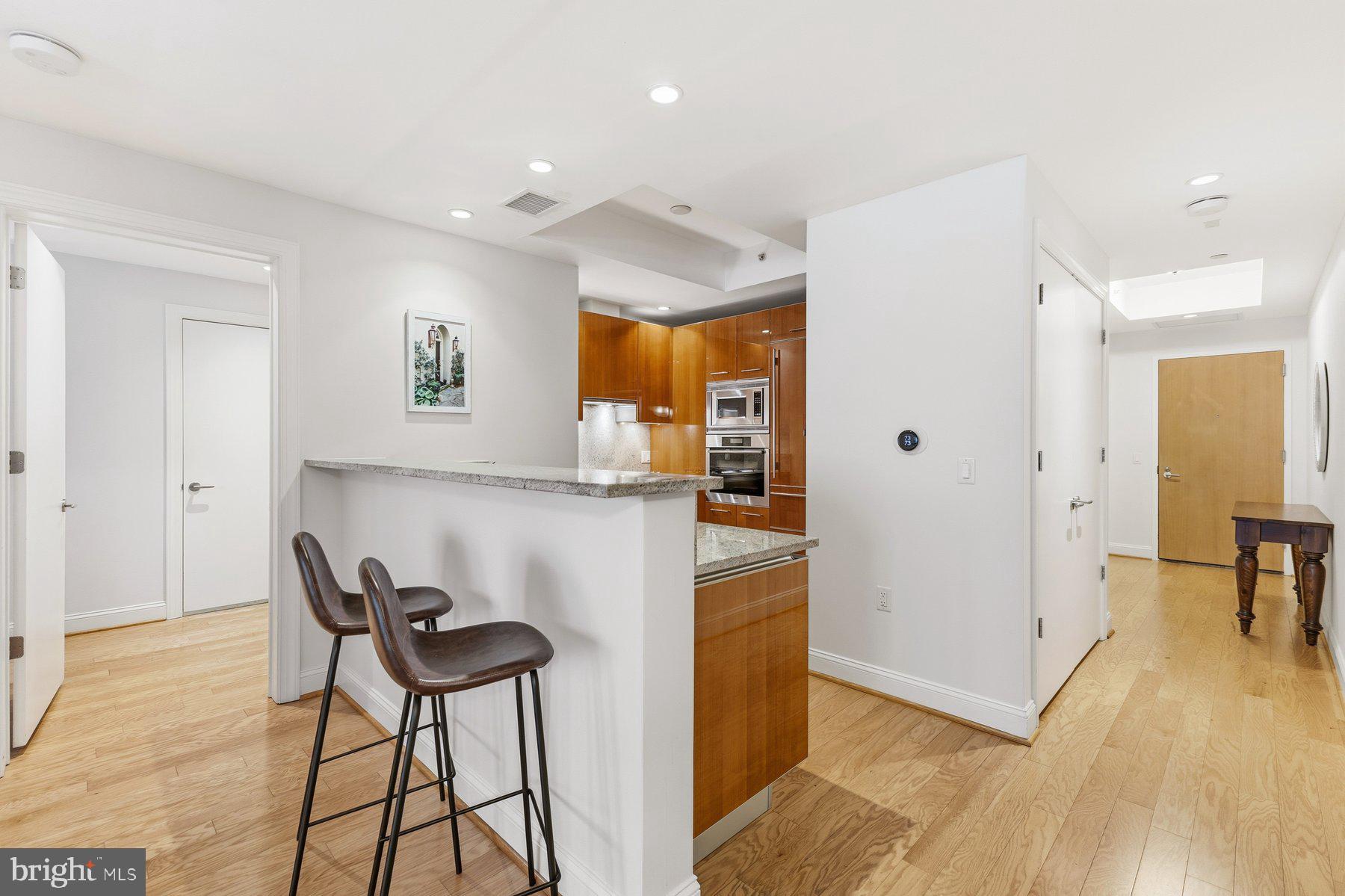 1881 North Nash Street, Unit 408 Arlington, VA 22209 - Photo 12 of 44 a kitchen with stainless steel appliances kitchen island granite countertop a refrigerator and a wooden cabinets