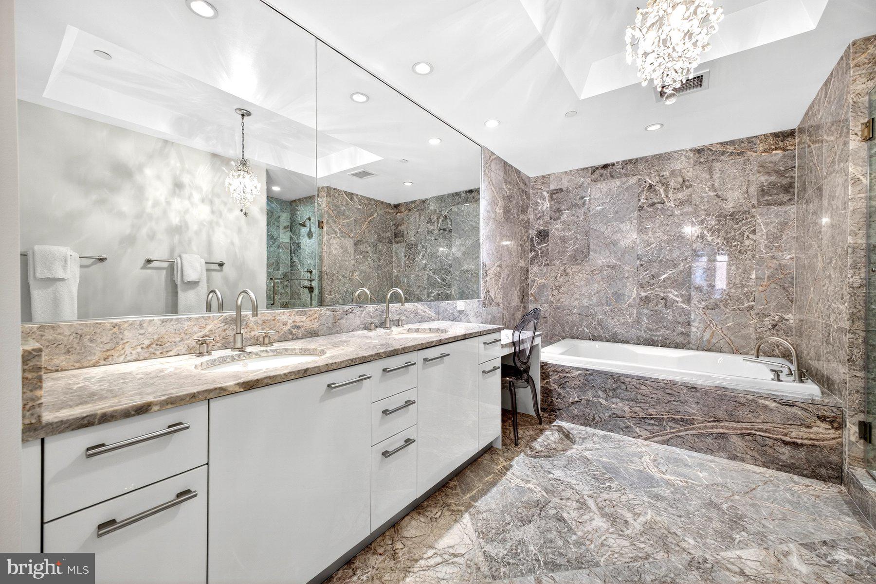 1881 North Nash Street, Unit 408 Arlington, VA 22209 - Photo 21 of 44 a bathroom with a granite countertop sink a large mirror and a bathtub