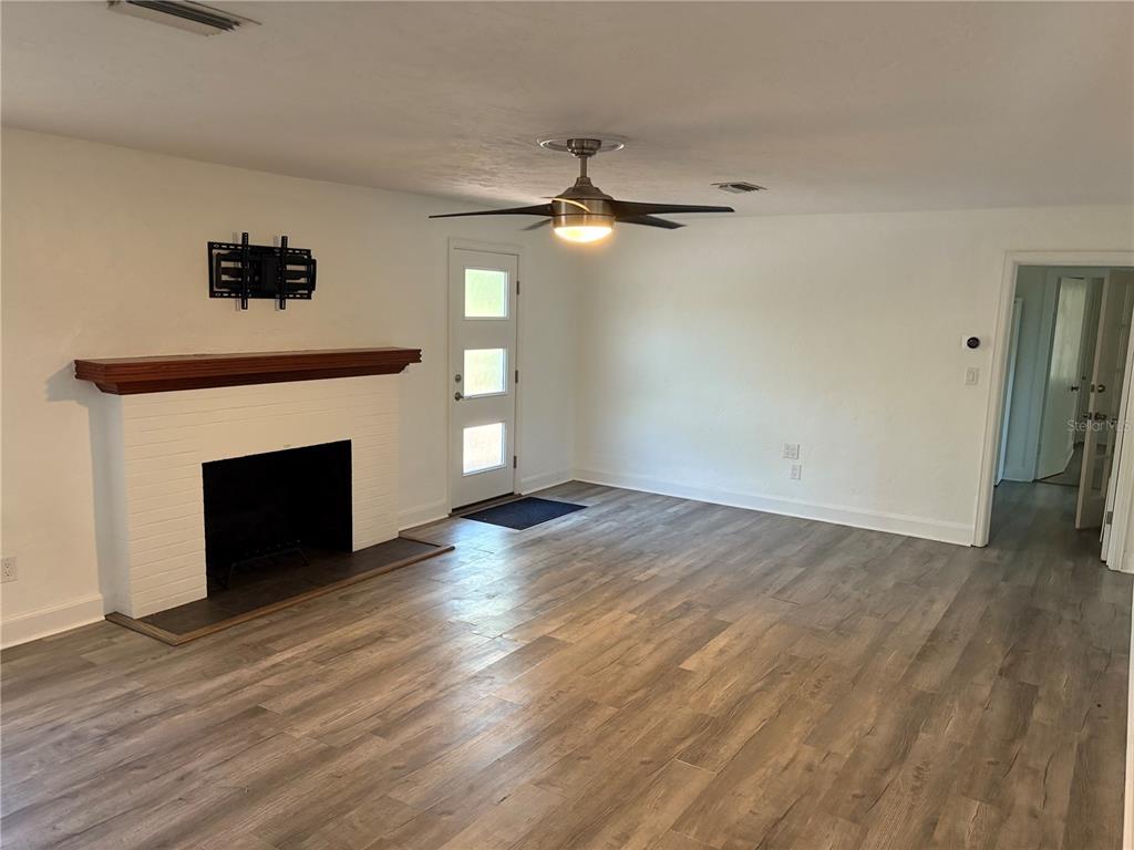 706 Northwest 20th Street Gainesville, FL 32603 - Photo 4 of 46 a view of empty room with wooden floor fireplace and fan